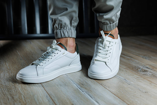 Casual white sneakers for men. Male legs in white leather summer shoes. Comfortable men's white sneakers with laces. - Foto, Bild