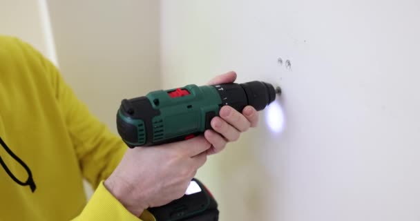 Worker unscrews fixture with electric screwdriver in premise. Repair and transformation of apartments. Builder removes screw from drywall slow motion - Footage, Video