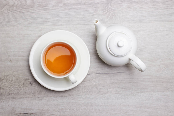 Cup of Tea and teapot, on a light wooden background - Foto, afbeelding