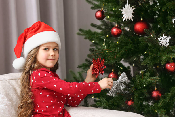 Cute girl decorating Christmas tree at home - Фото, изображение