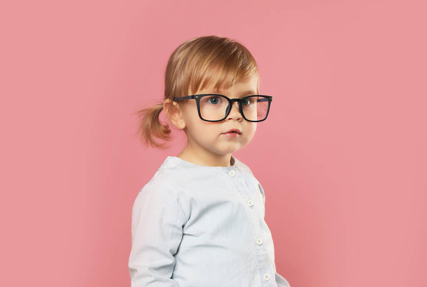 Cute little girl in glasses on pink background - Фото, зображення