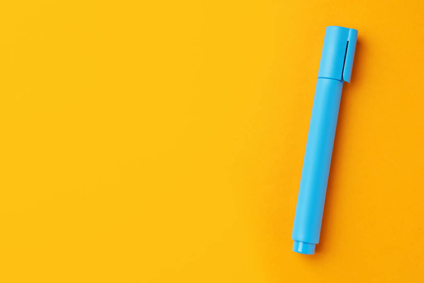 Bright light blue marker on orange background, top view. Space for text - Foto, Bild