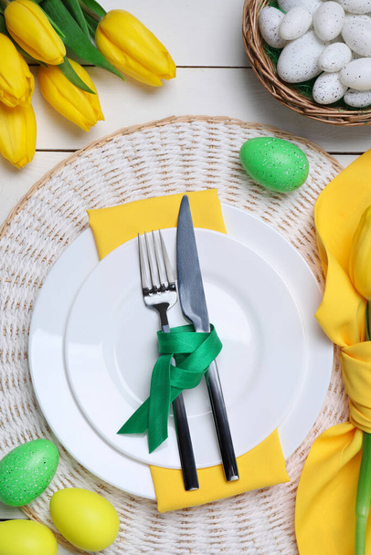 Festive table setting with painted eggs and tulips, flat lay. Easter celebration - Valokuva, kuva
