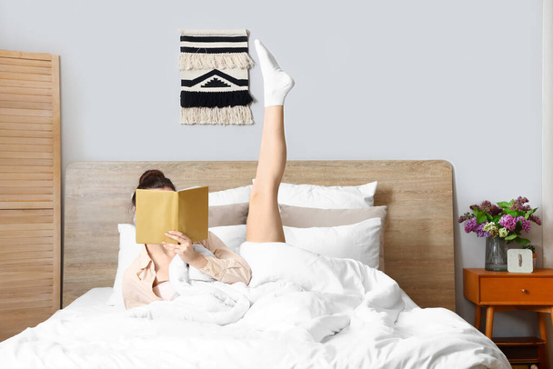 Πρωί της νεαρής γυναίκας ανάγνωση του βιβλίου στο κρεβάτι - Φωτογραφία, εικόνα