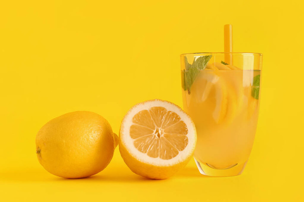 Glass with fresh lemonade and lemons on yellow background - Foto, imagen