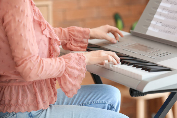Молода жінка-музикантка грає синтезатор вдома
 - Фото, зображення