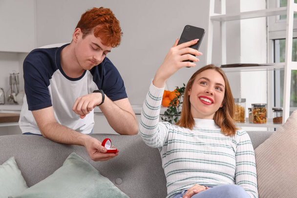 Wartender junger Mann macht Freundin mit Handy in Küche Heiratsantrag - Foto, Bild