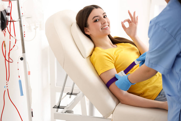 診療所で輸血のための若いドナーを準備する女性看護師 - 写真・画像