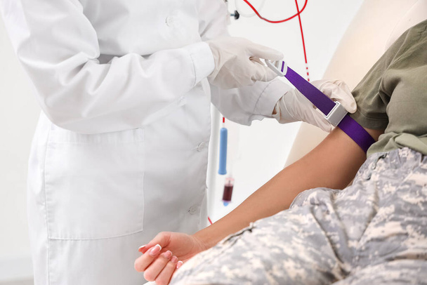 Γιατρός προετοιμασία γυναίκα στρατιώτης για μετάγγιση αίματος στην κλινική, closeup - Φωτογραφία, εικόνα