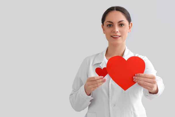 Médecin féminin avec des coeurs en papier sur fond clair. Concept de don de sang - Photo, image