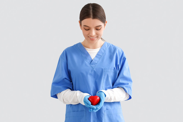 Female nurse with heart on light background. Blood donation concept - Fotografie, Obrázek
