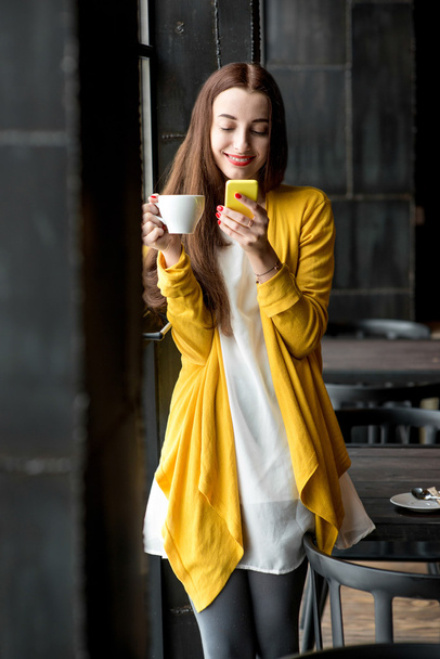 Donna con telefono e una tazza di caffè
 - Foto, immagini