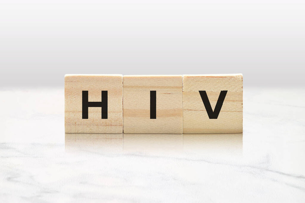 Houten tegels die hiv spellen tegen een minimalistische witte marmeren achtergrond - Foto, afbeelding