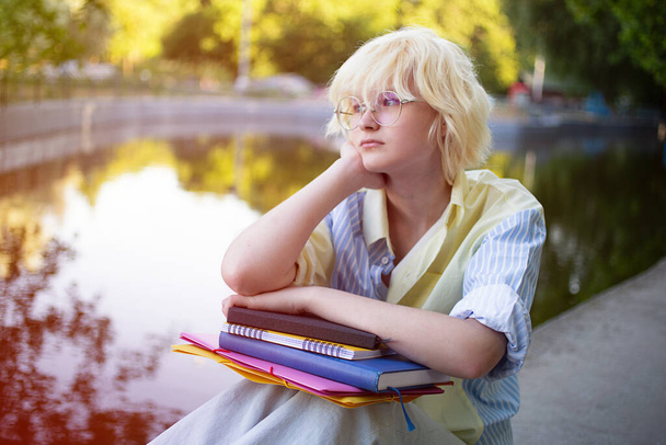 Teenage girl with folders deep in thoughts outdoor,closeup portrait. - Photo, Image