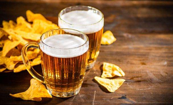 Fresh beer with corn chips. On rustic background. - Foto, imagen