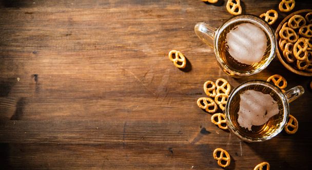 Beer in glasses with salted pretzels. On wooden background - Photo, image