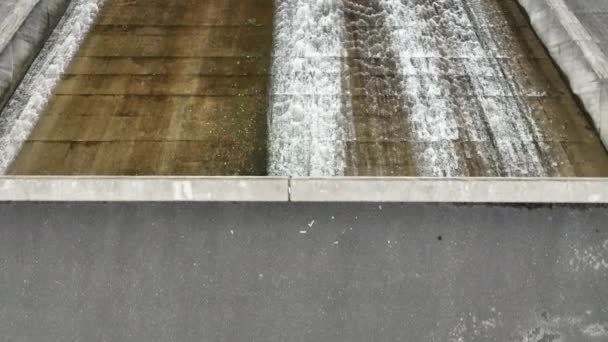 Vista de cima para baixo da água que desce o desfiladeiro da barragem para a piscina de concreto na floresta. Imagens 4k de alta qualidade - Filmagem, Vídeo