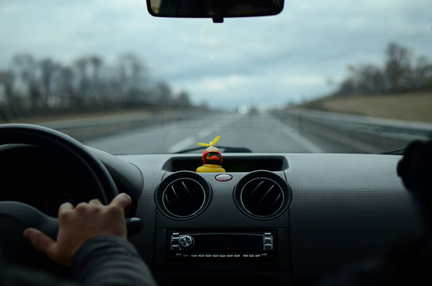 Photo of the road from the interior of the car with bokeh, lights and a rubber duck.Travel by car.View from the car.Track.Car windshield.Beautiful landscape.Yellow duck.Dashboard.Auto driving.motion.car trip.aesthetic photo on the road inside the car - Foto, Bild