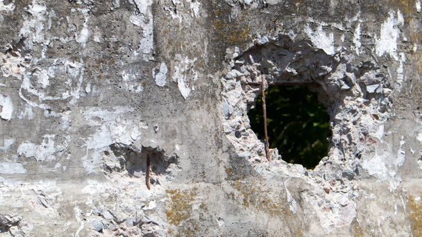 Foto einer kaputten Zementmauer oder eines Zaunes. Stone Grunge seltsame Wand mit einem Loch. Beschädigter Grunzbruch und kaputte Betonwand - Foto, Bild