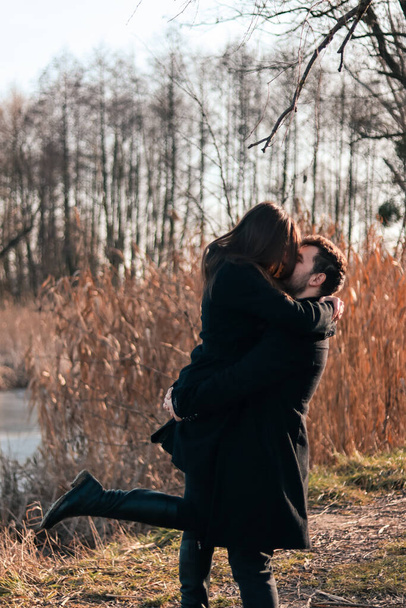 Man and woman in black clothes hugging.Love story.Love between a man and a woman.Photo in nature near the lake.Happy husband and wife.Black clothing style.Romantic photo in nature.love couple.Romantic date.Valentine's day.Romance.Happy family. - Fotografie, Obrázek