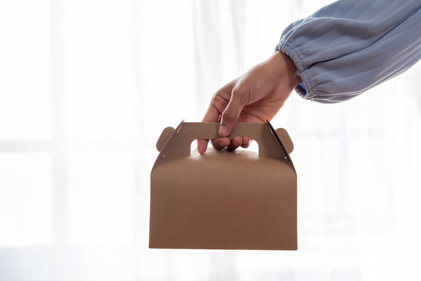 Ženská ruka drží recyklovatelnou krabici s jídlem na bílém pozadí. Mock-ups. - Fotografie, Obrázek
