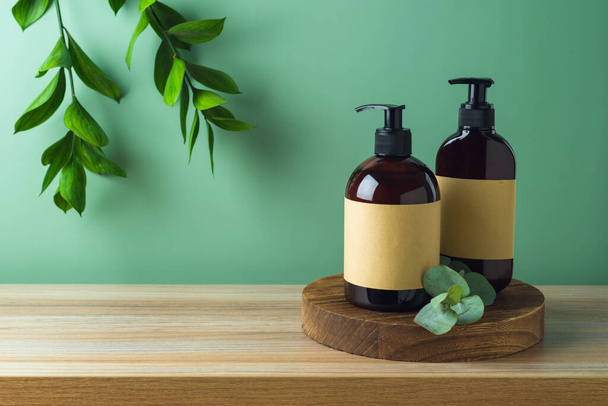 Natural cosmetics bottles with labels on wooden podium  for mock up packaging design over green wall background - Valokuva, kuva