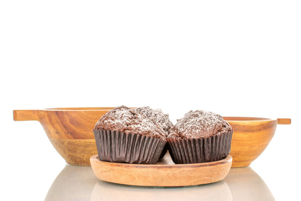 Dois muffins de chocolate caseiros em um pires de madeira com duas xícaras de madeira, macro, isolado em fundo branco. - Foto, Imagem