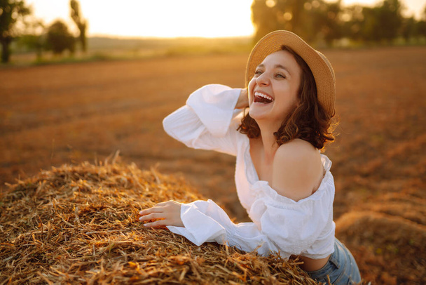 Beautiful woman near haystack at sunset. Nature, vacation, relax and lifestyle. - 写真・画像