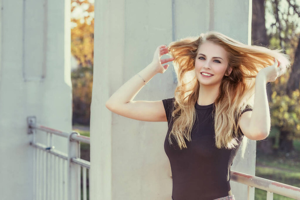 Attractive girl with flowing hair is  laughing at camera outdoors. Horizontally.  - Foto, Bild