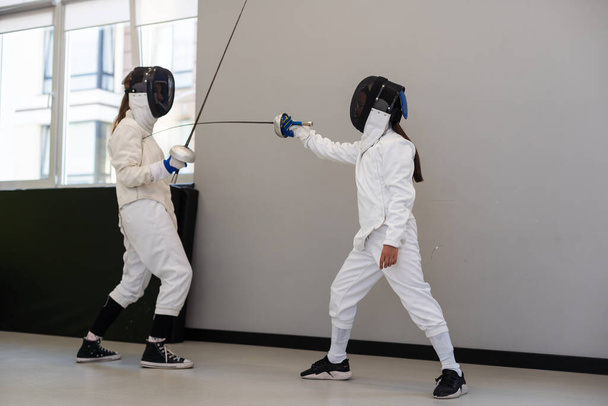 Two girl fencing athletes fight on professional sports arena . High quality photo - Photo, Image