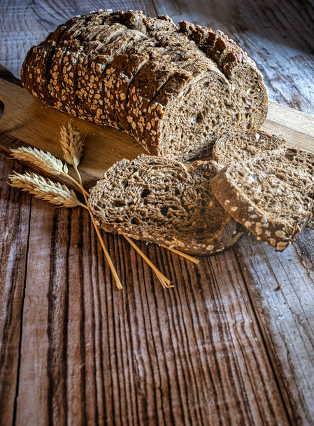 Slices of fresh bread and ears of corn on a rustic table - 写真・画像