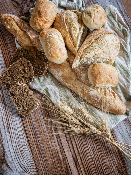 Bakery - rustic golden breads and buns on wooden background. Still life captured from above (top view, flat). - Photo, Image