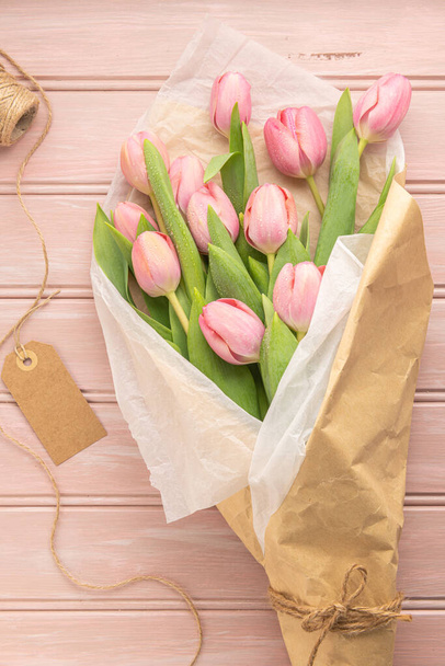 Bouquet de fleurs de tulipe rose sur fond de bois rose pâle. Couché à plat, vue de dessus. Concept floral printanier. - Photo, image