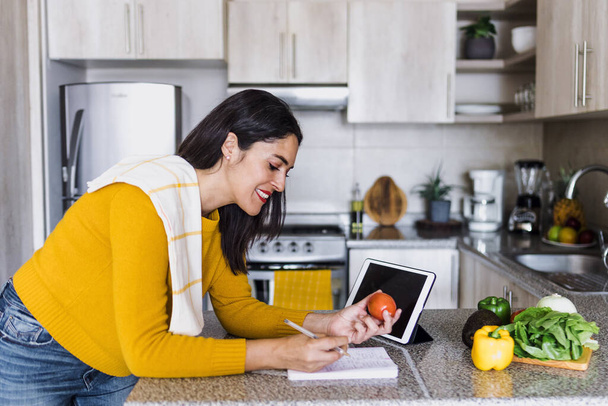 Latinská dospělá žena vaření a psaní recept v notebooku v kuchyni doma v Mexiku Latinská Amerika, hispánská žena - Fotografie, Obrázek