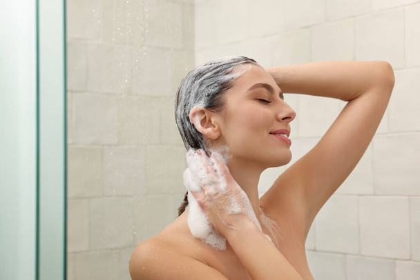 Happy woman washing hair while taking shower at home - Фото, зображення