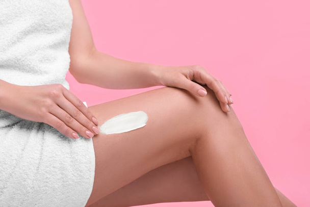 Woman with smear of body cream on her leg against pink background, closeup - Zdjęcie, obraz
