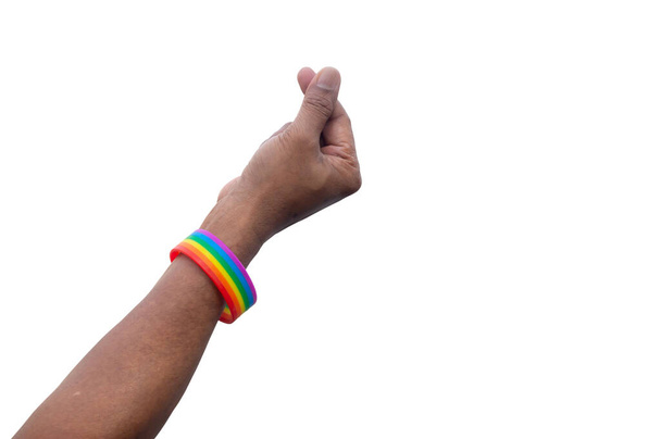 Hand trägt Regenbogen oder lgbtq + Symbol Armband streckt sich in der Luft mit Mini-Herz-Symbol für den Schutz und die Unterstützung der geschlechtsspezifischen Vielfalt oder lgbtq + Menschen und Gemeinschaft ist auf weißem Hintergrund mit Clipping-Pfad isoliert. - Foto, Bild