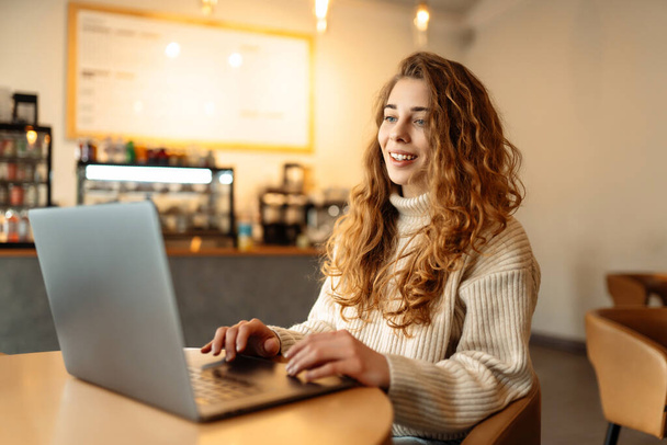 Młoda kobieta z laptopem w kawiarni. Biznes, blogi, freelancing, koncepcja edukacji. - Zdjęcie, obraz