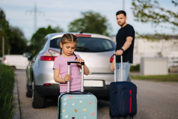 Retrato de una niña adorable con su padre de pie con maletas delante del coche. Foto de alta calidad - Foto, Imagen