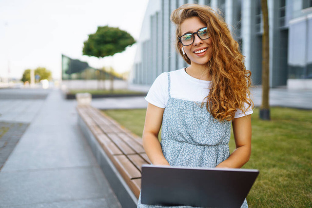 Young woman working online on laptop computer outdoor. Business, blogging, freelance, education concept. - Fotó, kép