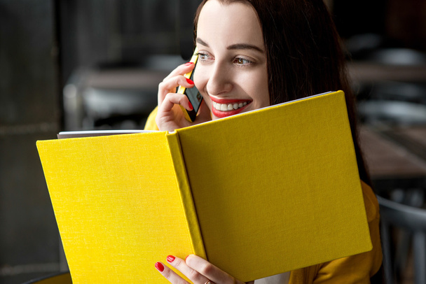 Vrouw met boek en mobiele telefoon - Foto, afbeelding