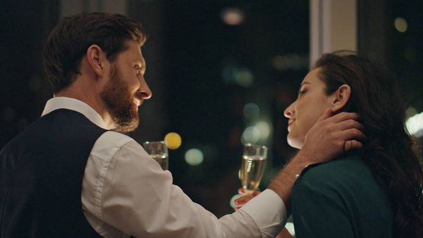 Couple lovers flirting on date drinking champagne at window closeup. Bearded man touching gently woman face seducing attractive girl. Two people in love enjoy romantic relationship relax late evening. - Photo, Image