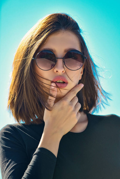 Female fashion model posing with sunglasses. Close-up portrait of a beautiful charming young attractive lady. Portrait of serious woman in the light isolated. Beauty and fashion - Zdjęcie, obraz