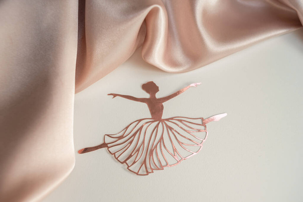 Paper pink ballerina performing a pirouette on a background of pink draped fabric. Background picture - Photo, Image