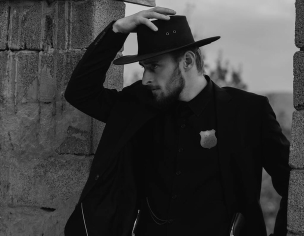 Sheriff or cowboy in black suit and cowboy hat. Man with west vintage pistol revolver gun. American western, sheriff - Fotó, kép
