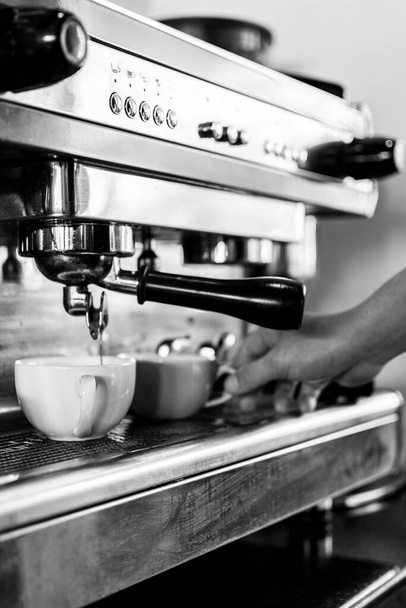 professionele barista met behulp van klassieke espresso koffiezetapparaat close-up in zwart-wit - Foto, afbeelding