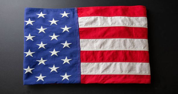 Amerykańska flaga złożona na czarnym terenie, widok z góry. Amerykańskie Święto Narodowe, Dzień Pamięci i Niepodległości - Zdjęcie, obraz