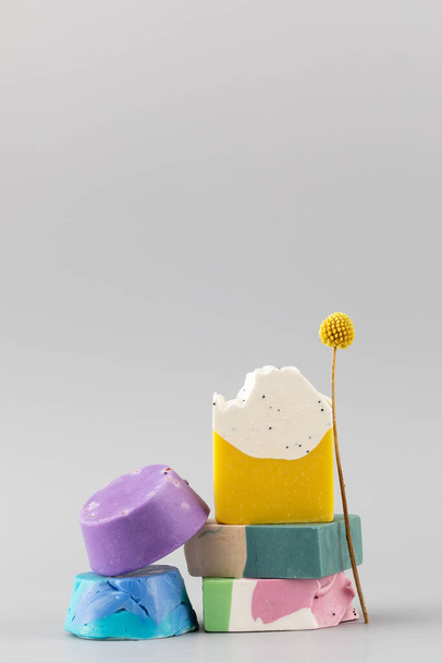Pieces of different shapes and colors of handmade soap on a grey background. The concept of natural cosmetics, hygiene. Copy space - Foto, Imagem