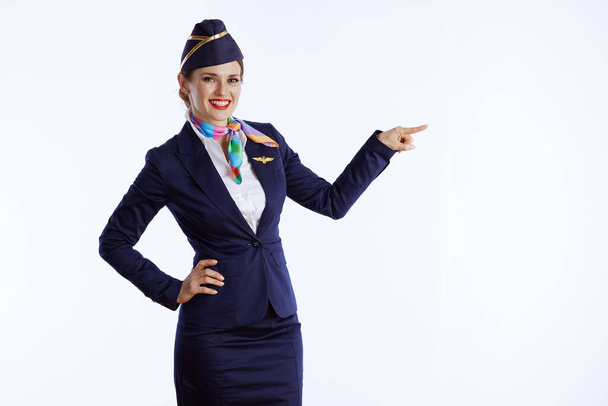 smiling stylish air hostess woman isolated on white background in uniform pointing at copy space. - Foto, Imagen