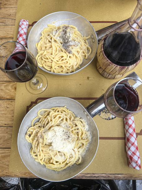 Italiaans eten, bovenaanzicht heerlijke handgemaakte pasta met kaas op tafel. typische en traditionele Italiaanse spaghetti en lokale rode wijn op tafel in Rome, Italië. spaghetti carbonara en rode wijn in Rome - Foto, afbeelding